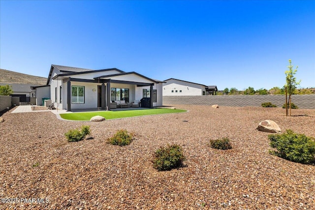 view of front of home with stucco siding, a patio area, a fenced backyard, and an outdoor hangout area