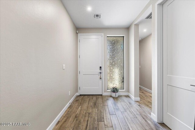 doorway to outside with wood finished floors, visible vents, and baseboards