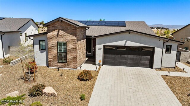 ranch-style home with solar panels, driveway, fence, a garage, and stucco siding