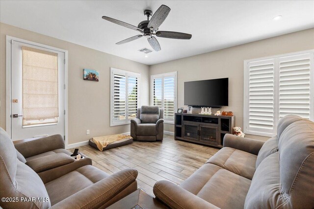 living room with wood finished floors, visible vents, baseboards, and ceiling fan