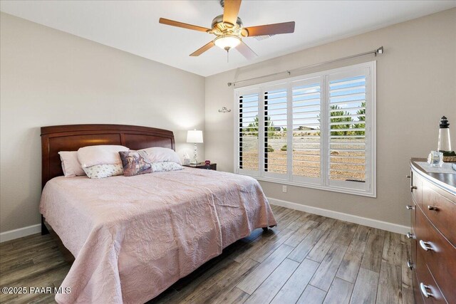 bedroom featuring wood finished floors, a ceiling fan, and baseboards