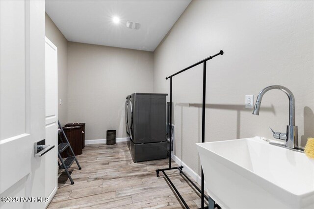 laundry room featuring washer and clothes dryer, laundry area, a sink, light wood-type flooring, and baseboards