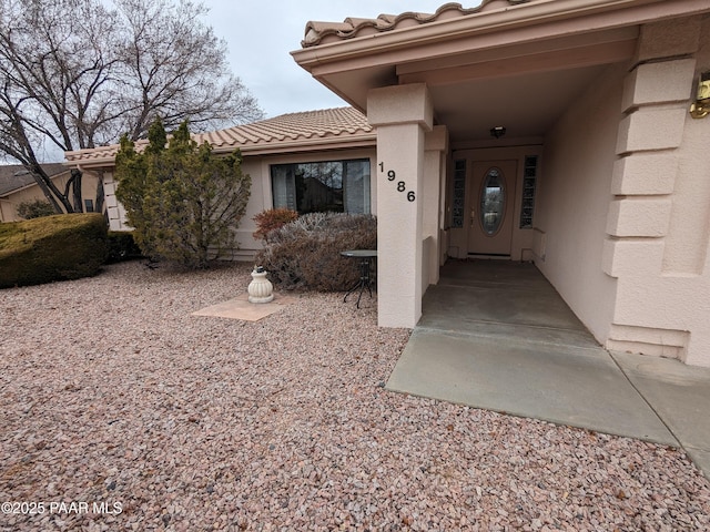 property entrance featuring stucco siding and a tile roof