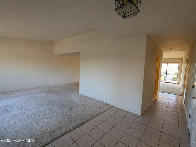 spare room with baseboards, light colored carpet, and light tile patterned floors