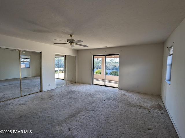 unfurnished bedroom with carpet floors, two closets, multiple windows, and access to exterior