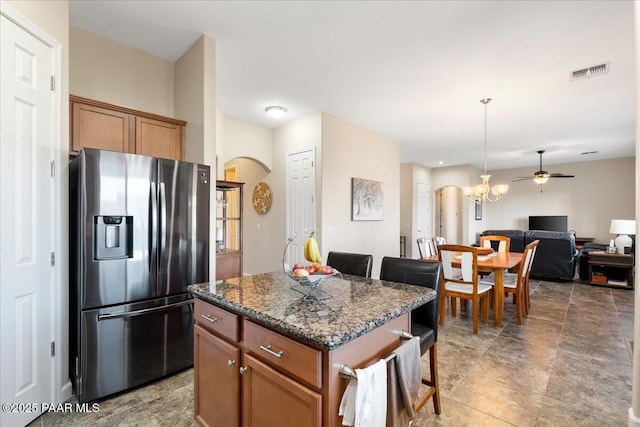 kitchen featuring a kitchen bar, arched walkways, a kitchen island, and stainless steel refrigerator with ice dispenser