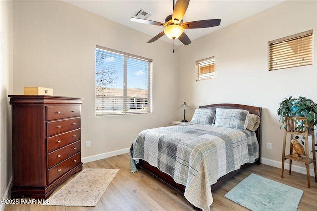 bedroom with visible vents, baseboards, wood finished floors, and a ceiling fan