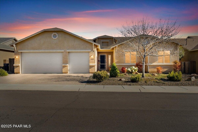 view of front of property with concrete driveway, an attached garage, and stucco siding