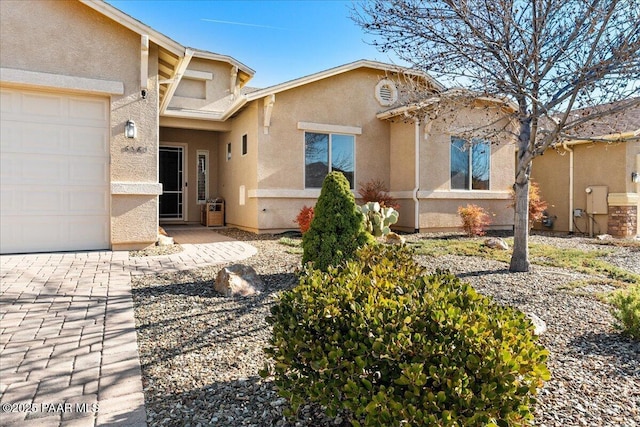 view of front of home with stucco siding, a garage, and driveway