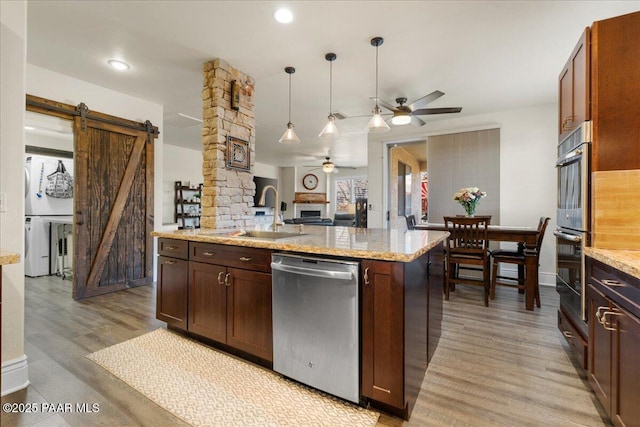 6969 E Encampment Dr, Prescott Valley, AZ 86314 - kitchen with appliances with stainless steel finishes, decorative light fixtures, sink, light hardwood / wood-style floors, and a barn door