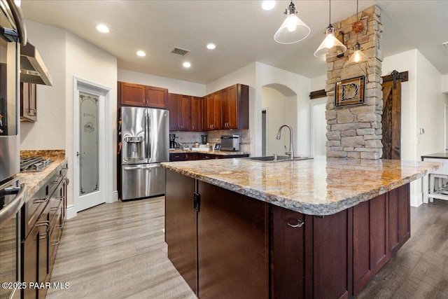 6969 E Encampment Dr, Prescott Valley, AZ 86314 - kitchen featuring sink, hanging light fixtures, stainless steel appliances, light stone counters, and light hardwood / wood-style floors