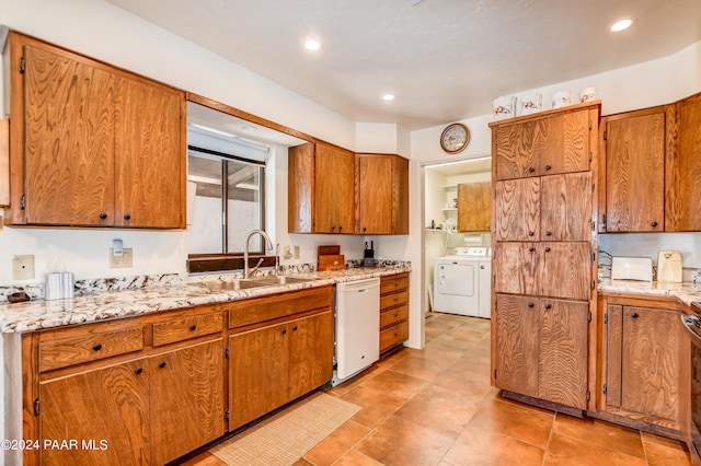 kitchen with light stone countertops, sink, white dishwasher, and washer and dryer