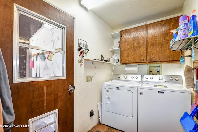 laundry area featuring washer and clothes dryer, light tile patterned floors, and cabinets