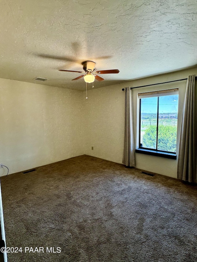 empty room with carpet flooring, ceiling fan, and a textured ceiling