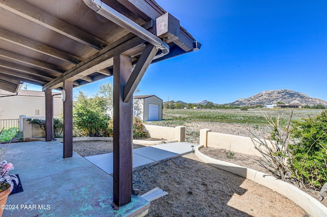 view of patio with a mountain view, a garage, and an outbuilding