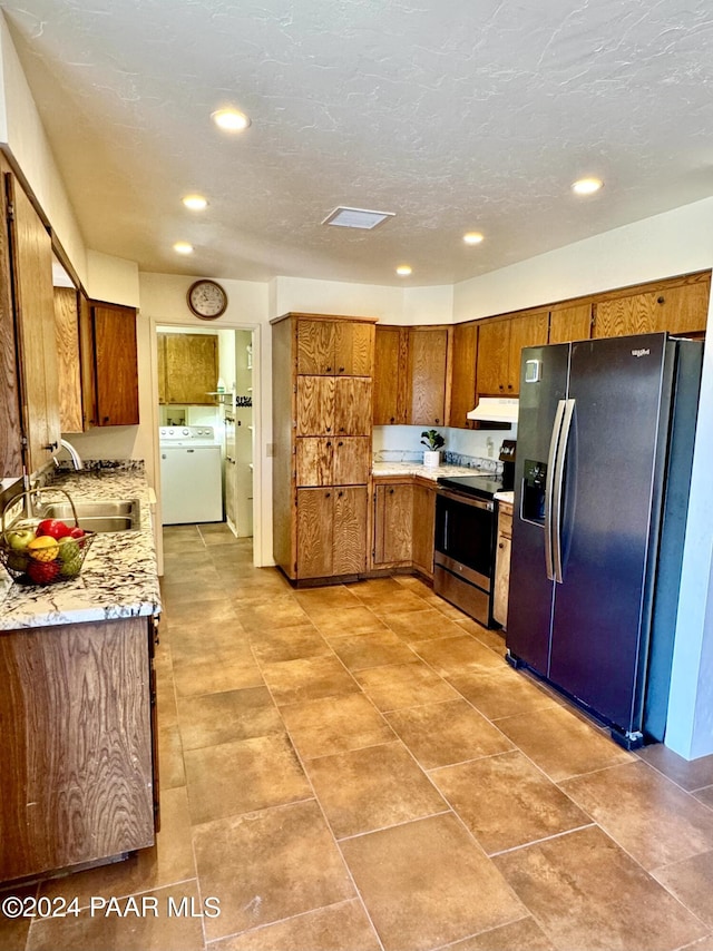 kitchen featuring light stone counters, stainless steel appliances, sink, exhaust hood, and washer / dryer