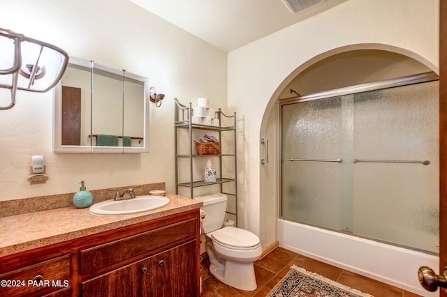 full bathroom featuring toilet, tile patterned flooring, vanity, and combined bath / shower with glass door