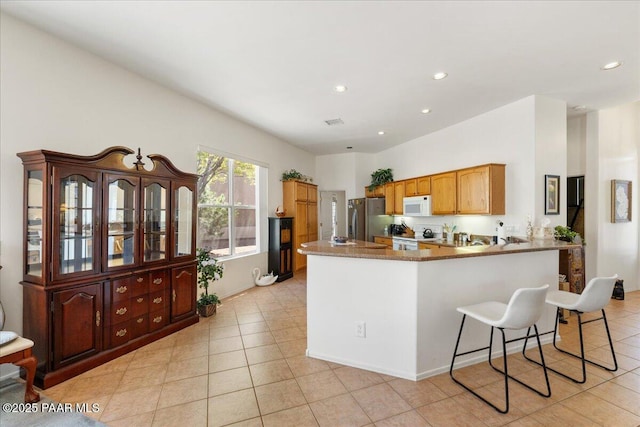 515 S Camino De Encanto, Cornville, AZ 86325 - kitchen with white appliances, a peninsula, light tile patterned floors, recessed lighting, and a kitchen bar