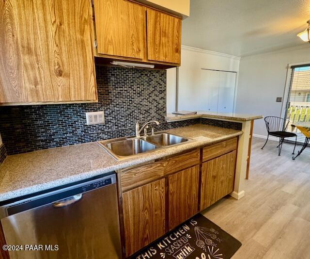 kitchen with dishwasher, a sink, tasteful backsplash, crown molding, and light wood-style floors