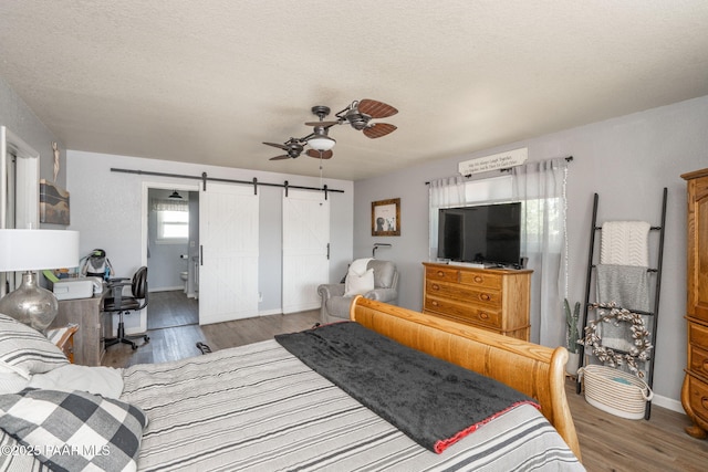 11755 Hondo Hts, Dewey-Humboldt, AZ 86327 - bedroom with a barn door, wood finished floors, baseboards, a textured ceiling, and a ceiling fan