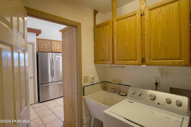 washroom with cabinets, light tile patterned floors, sink, and washer / clothes dryer