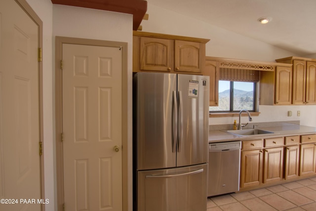 kitchen with sink, stainless steel appliances, vaulted ceiling, light brown cabinetry, and light tile patterned flooring