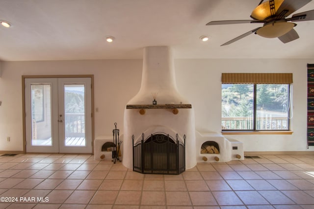 unfurnished living room featuring a large fireplace, ceiling fan, french doors, and light tile patterned flooring