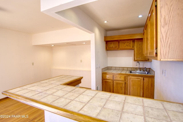 kitchen featuring tile countertops, hardwood / wood-style flooring, and sink