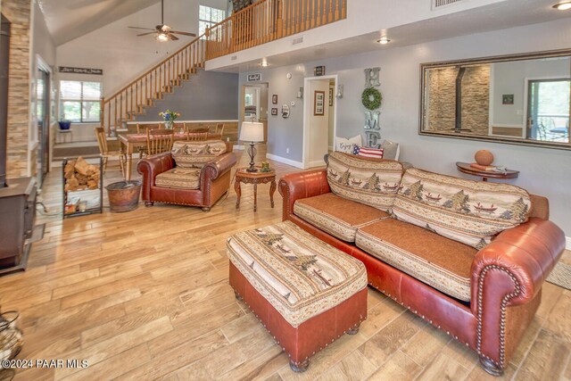 living room featuring ceiling fan, plenty of natural light, high vaulted ceiling, and light wood-type flooring