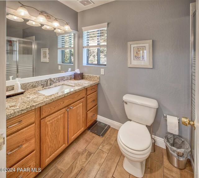 bathroom featuring vanity, toilet, wood-type flooring, and walk in shower