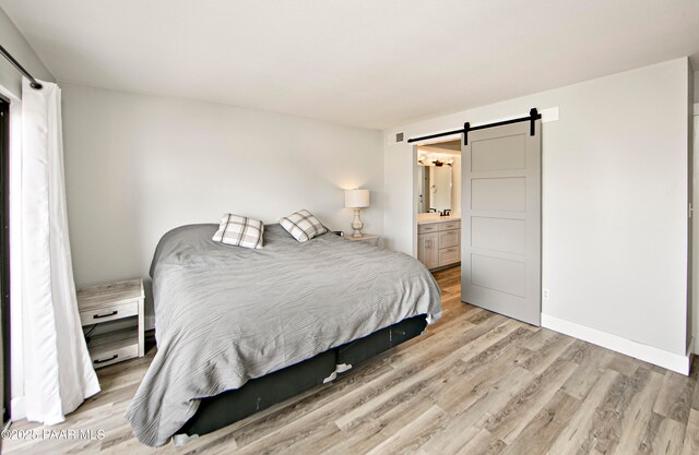 2151 S Resort Way Unit 1C, Prescott, AZ 86301 - bedroom featuring light wood-type flooring, baseboards, connected bathroom, a barn door, and visible vents