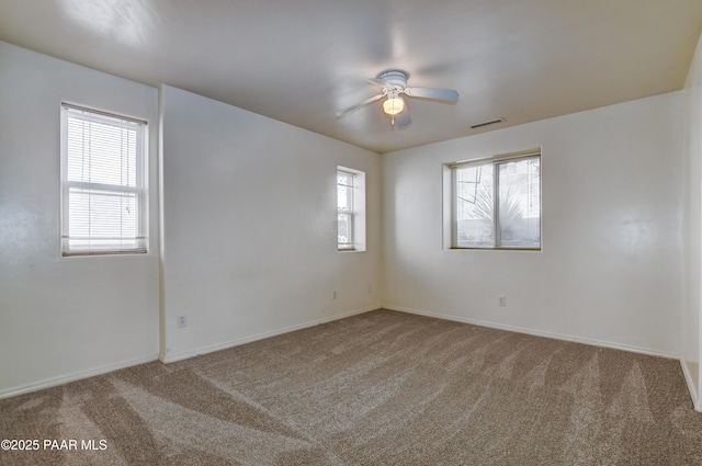 carpeted spare room featuring ceiling fan and plenty of natural light