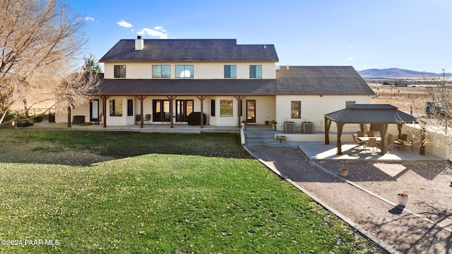 rear view of property with a yard, central air condition unit, a mountain view, a gazebo, and a patio