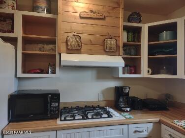 kitchen featuring black microwave, light countertops, white cabinets, white gas cooktop, and under cabinet range hood