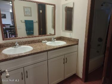 bathroom featuring a sink, double vanity, and shower / washtub combination