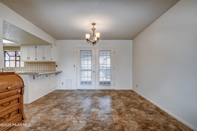 3718 N Navajo Dr, Prescott Valley, AZ 86314 - unfurnished dining area featuring an inviting chandelier, french doors, stone finish flooring, baseboards, and a textured ceiling