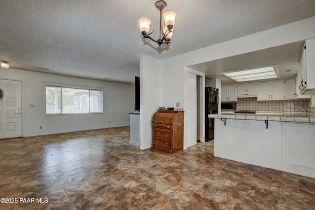 3718 N Navajo Dr, Prescott Valley, AZ 86314 - kitchen featuring tile countertops, freestanding refrigerator, a peninsula, open floor plan, and a notable chandelier