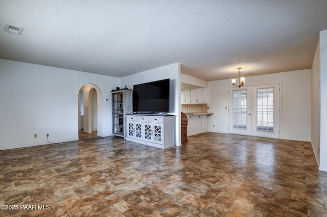 3718 N Navajo Dr, Prescott Valley, AZ 86314 - unfurnished living room with arched walkways, visible vents, a chandelier, and a textured ceiling