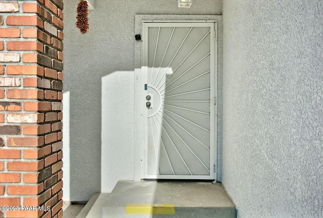 property entrance with brick siding and stucco siding