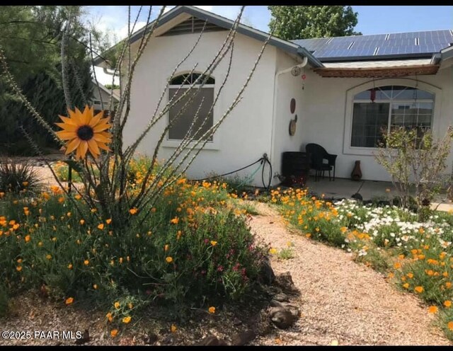 view of home's exterior with solar panels, a patio, and stucco siding