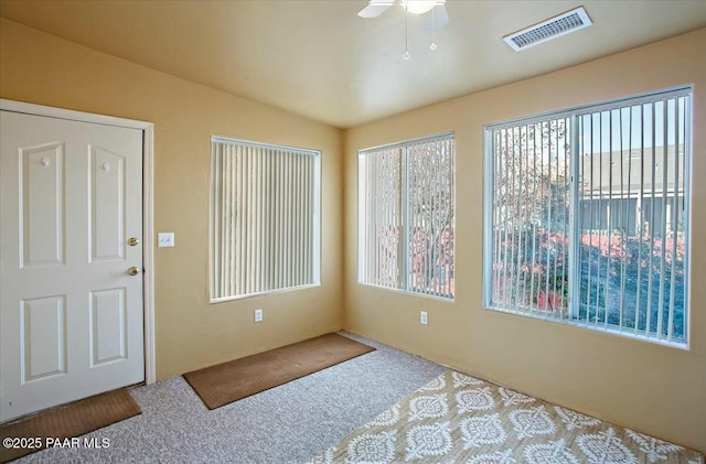 carpeted foyer with a ceiling fan, lofted ceiling, and visible vents