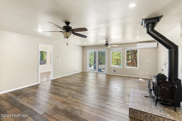 4820 S Lund Ct, Prescott, AZ 86303 - living area with a wood stove, a ceiling fan, a wall unit AC, wood-type flooring, and a textured ceiling
