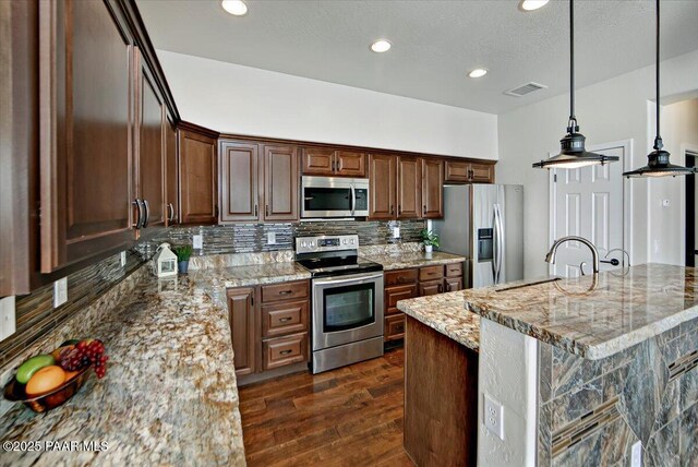 7273 Woolsey Ranch Rd, Prescott Valley, AZ 86314 - kitchen with stainless steel appliances, dark wood-type flooring, tasteful backsplash, light stone countertops, and decorative light fixtures