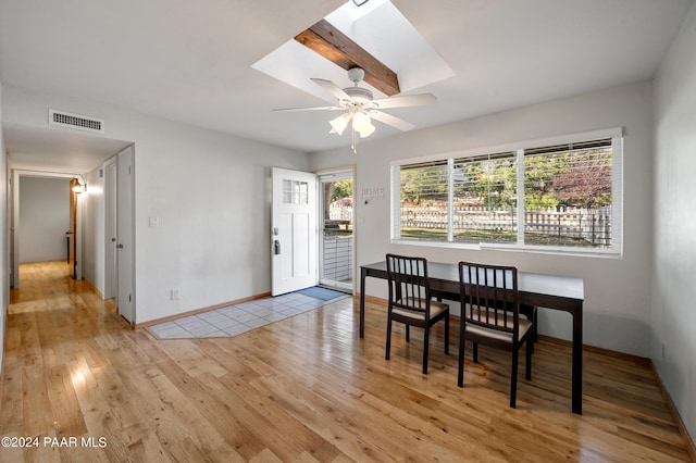 dining area with ceiling fan, a skylight, and light hardwood / wood-style flooring