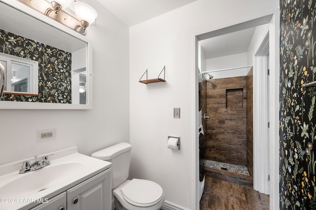 bathroom featuring tiled shower, vanity, hardwood / wood-style flooring, and toilet