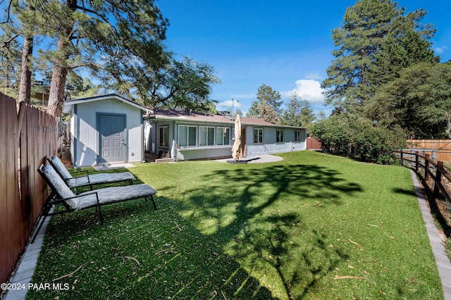 rear view of property with a storage shed and a lawn