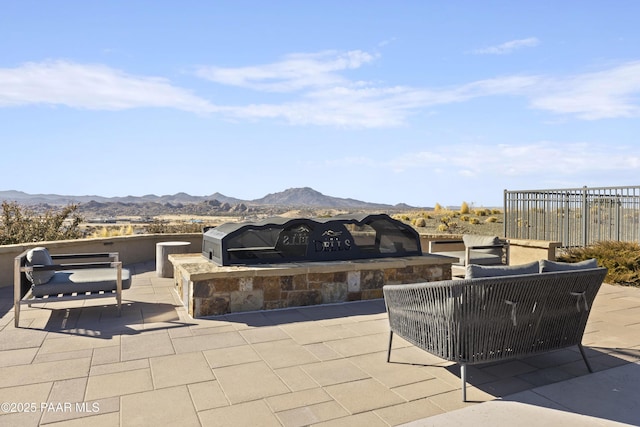 view of patio / terrace featuring a mountain view, outdoor lounge area, exterior kitchen, and fence