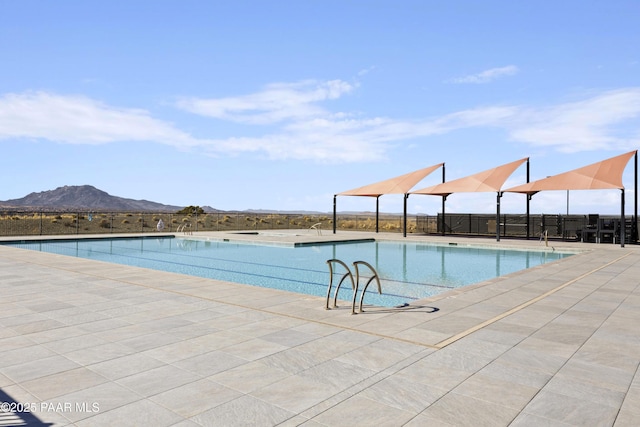 pool with a mountain view, a patio area, and fence