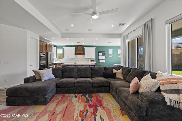 living room featuring visible vents, light wood-style flooring, a ceiling fan, recessed lighting, and baseboards