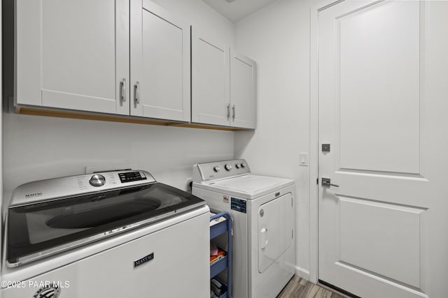 laundry area featuring cabinet space, separate washer and dryer, and light wood-style flooring